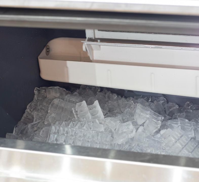 Open stainless steel ice machine showing ice bin and fresh ice cubes inside